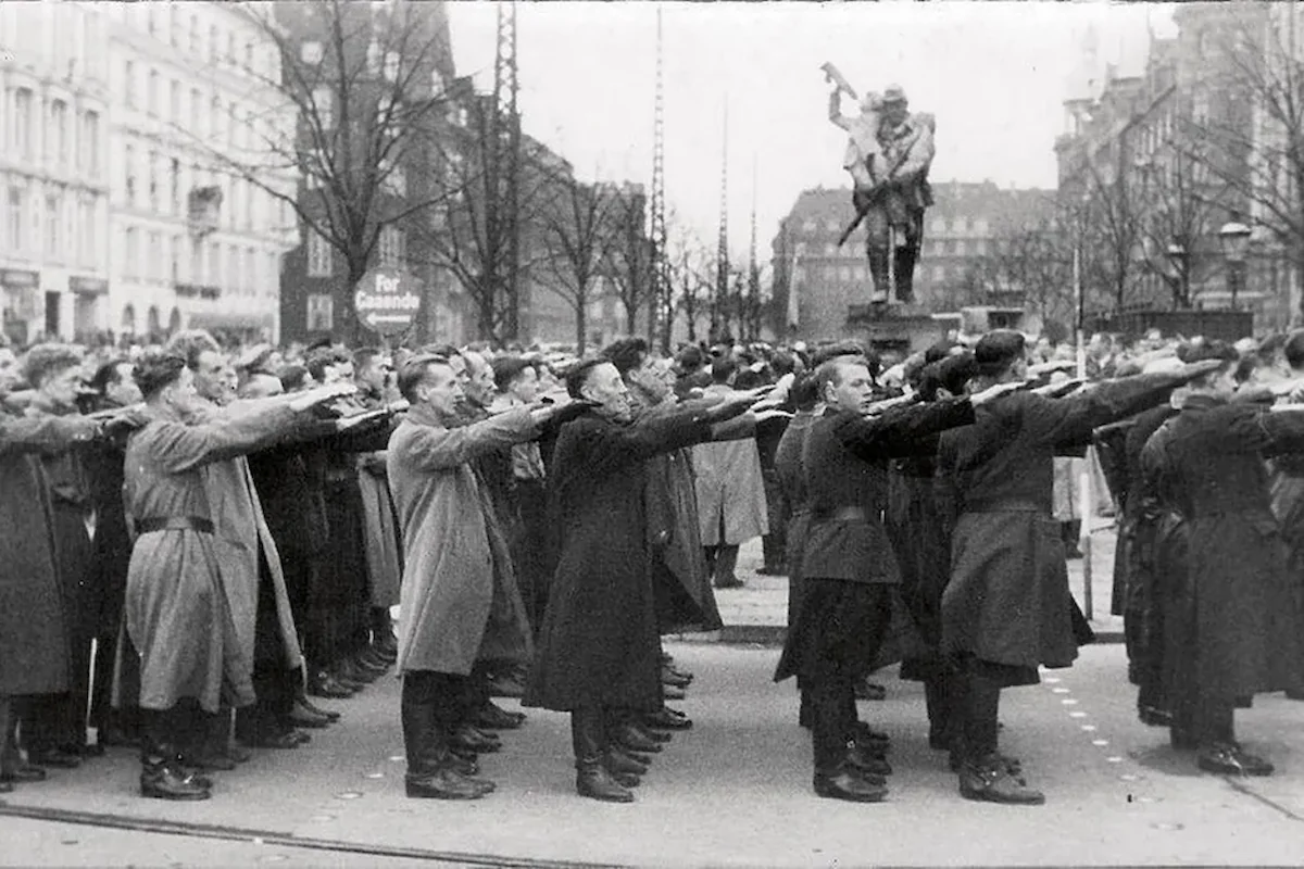 København 1940: Danmark besættes. Den 17. november 1940 samledes det danske nazistparti, DNSAP, foran statuen Den Lille Hornblæser i håb om at komme til magten. Overfor ligger Dagmarhus, der ligner sig selv i dag – bortset fra luftværnsbatterierne, der fyldte på bygningens tag under besættelsen. (Foto: fra bogen Turen går til besættelsestidens København)